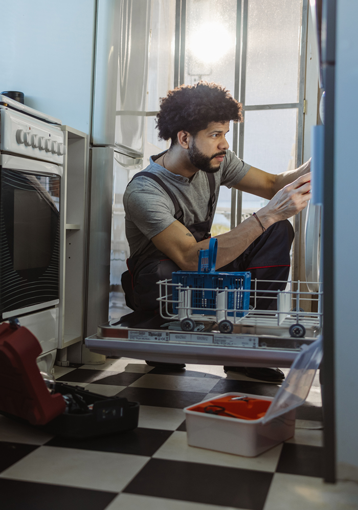 Photo of young handyman fixes dishwasher. Handyman service